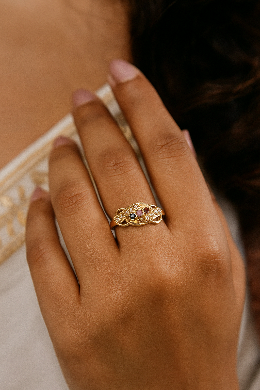 Gold ring with a gemstone on a person's finger against a blurred background