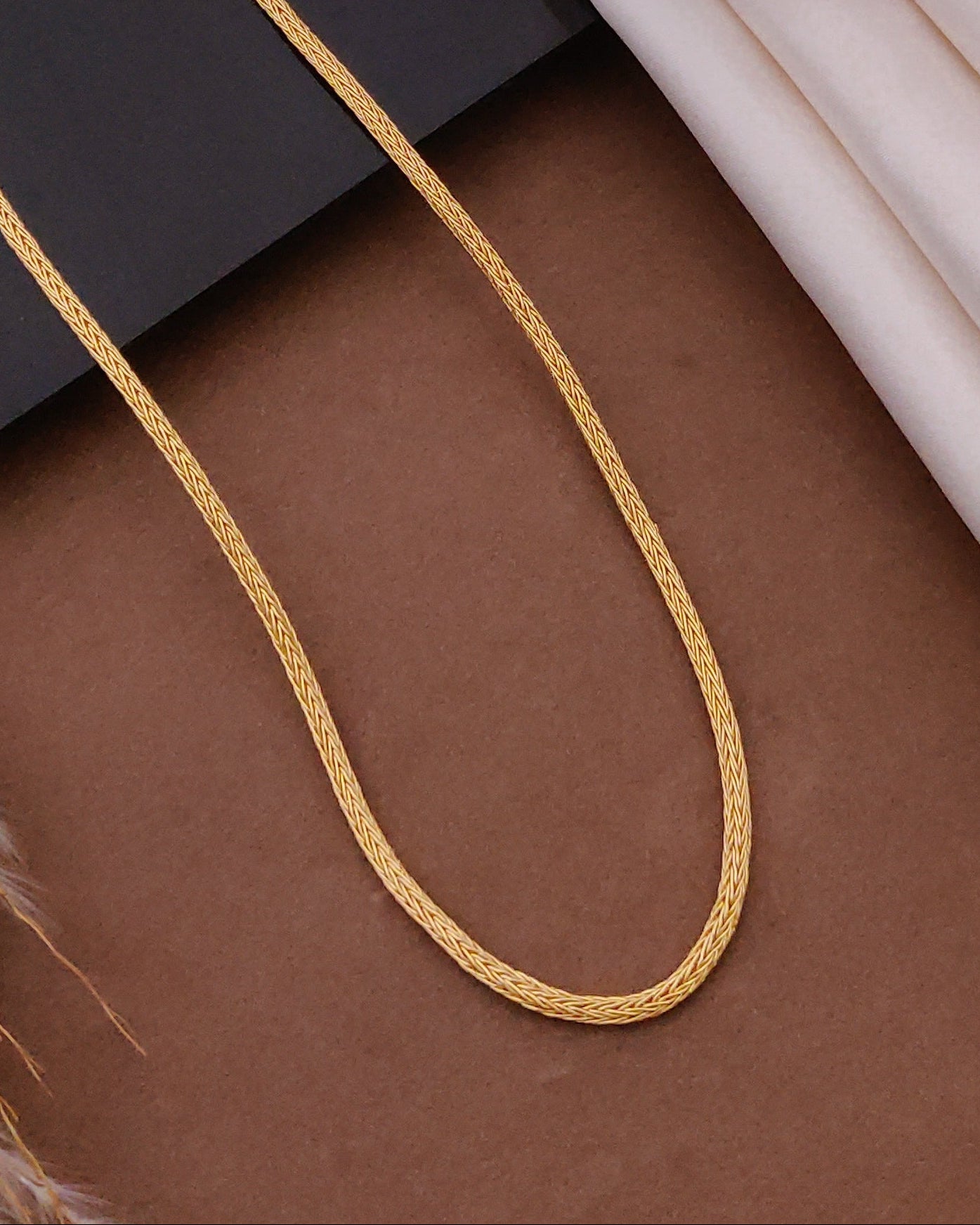 Gold chain on a surface with picture frames in the background