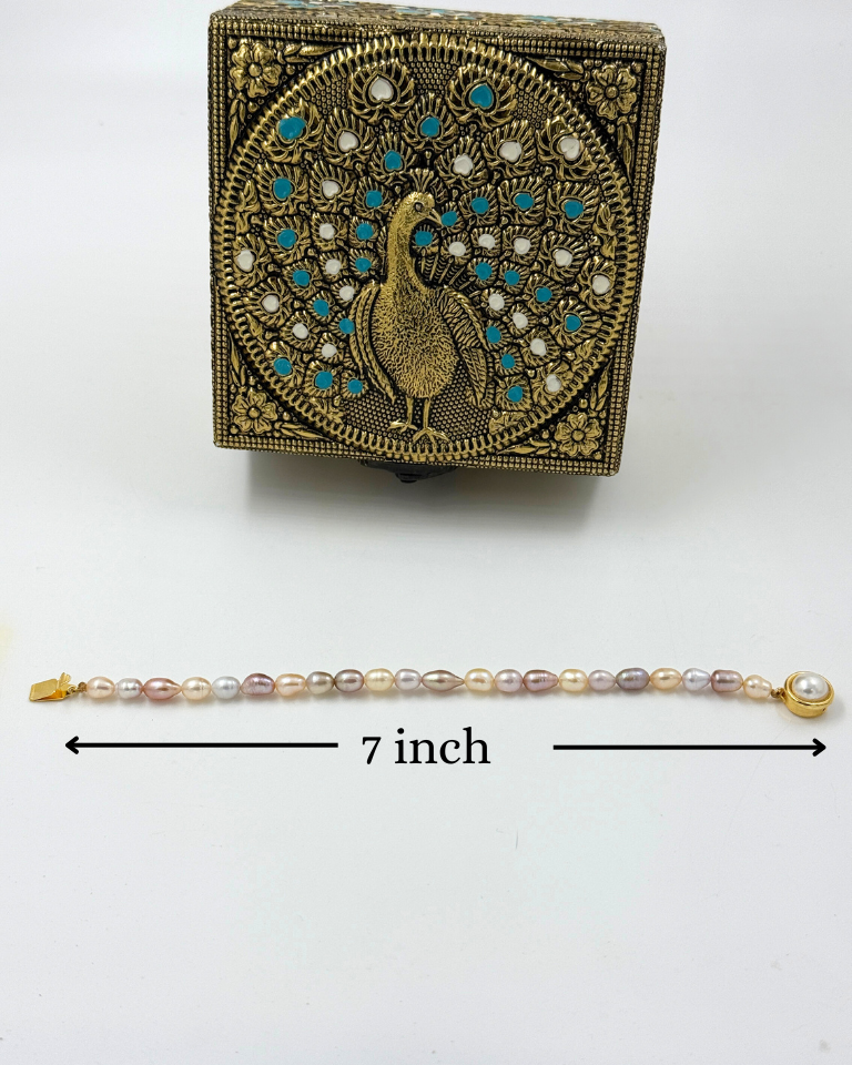 Decorative box with peacock design and pearl bracelet on a white background