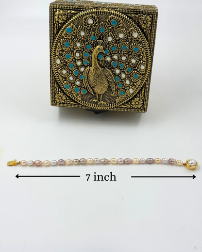 Decorative box with peacock design and pearl bracelet on a white background