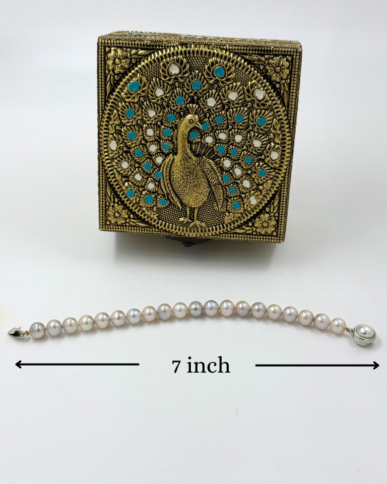 Decorative box with peacock design and pearl bracelet on a white background