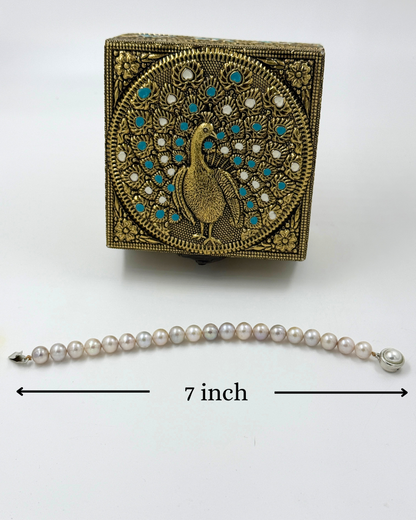 Decorative box with peacock design and pearl bracelet on a white background