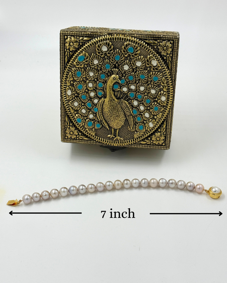 Decorative box with peacock design and pearl necklace on a white background