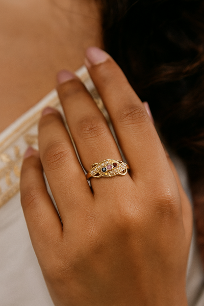 Gold ring with a gemstone on a person's finger against a blurred background