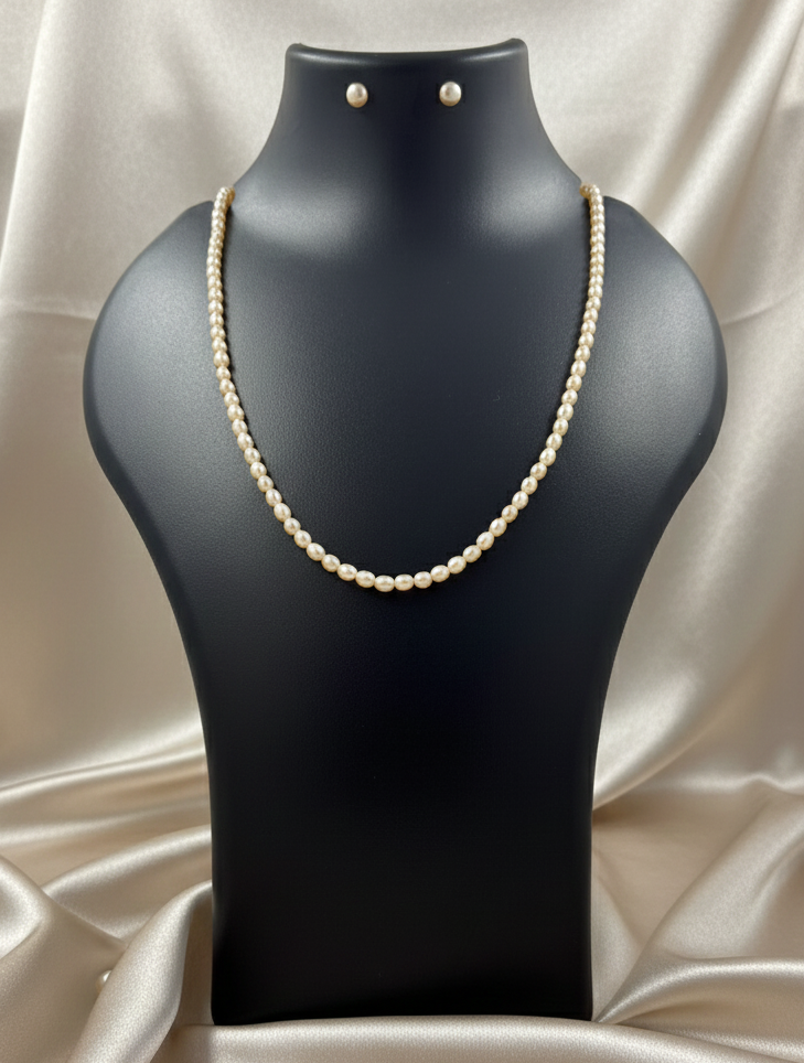 Pearl necklace and earrings on a black mannequin bust with a beige satin background