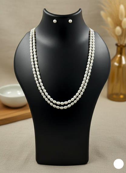 Pearl necklace on a black mannequin with earrings, set against a neutral background.
