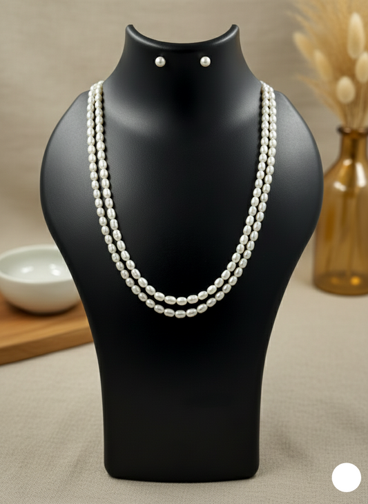 Pearl necklace on a black mannequin with earrings, set against a neutral background.