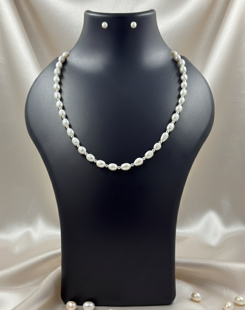 Pearl necklace on a black mannequin bust with scattered pearls on a satin background