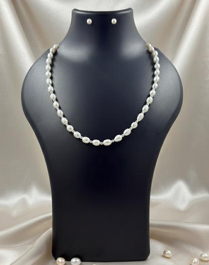 Pearl necklace on a black mannequin bust with scattered pearls on a satin background