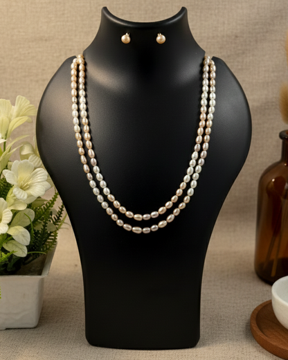 Pearl necklace and earrings on a black mannequin bust with a neutral background