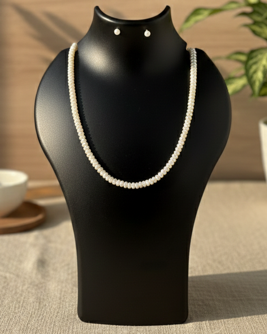 Black jewelry stand with a pearl necklace on a neutral background