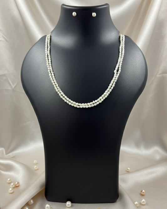 Pearl necklace on a black mannequin bust with scattered pearls on a satin background
