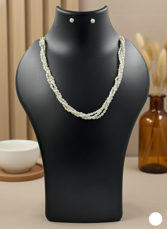 Pearl necklace on a black mannequin bust with earrings, against a neutral background.