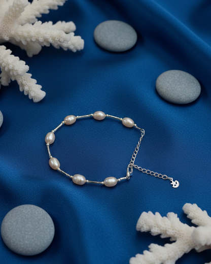 Pearl bracelet on a blue fabric background with white coral and stones
