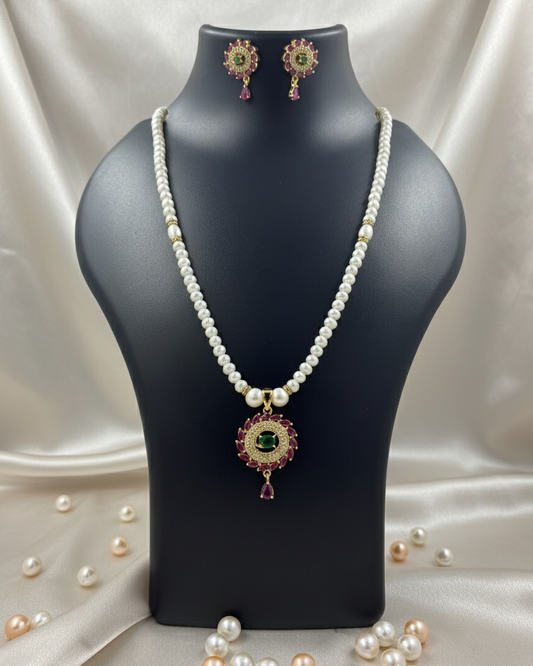 Pearl necklace with pendant and matching earrings on a black mannequin bust.