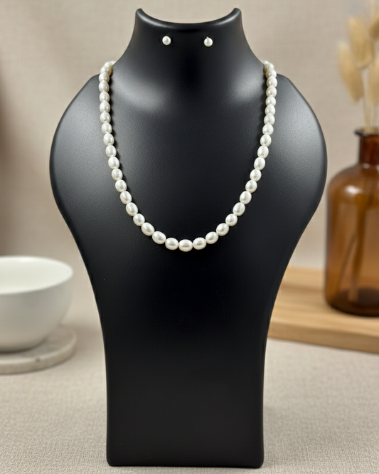 Pearl necklace on a black mannequin bust with a neutral background
