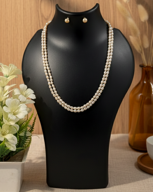 Pearl necklace on a black mannequin bust with a wooden background