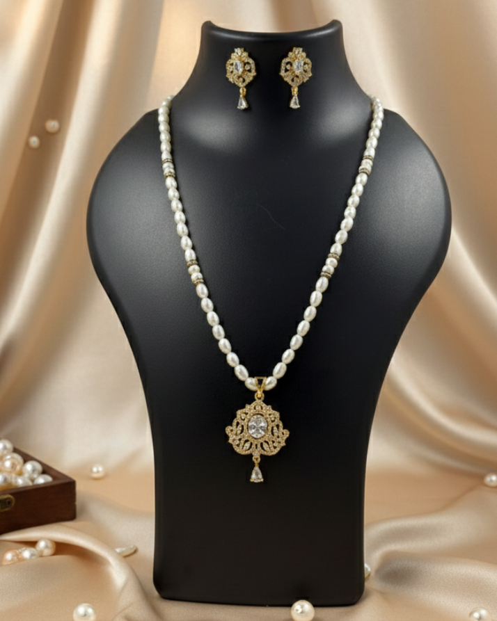 Pearl necklace and earrings on a black mannequin bust with scattered pearls on a beige fabric background.