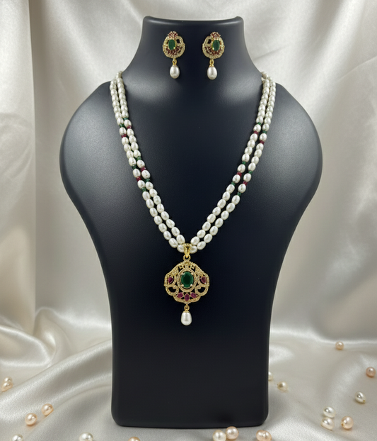 Pearl necklace with a pendant on a black mannequin bust, surrounded by scattered pearls.