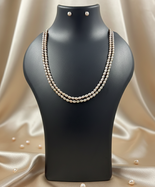 Pearl necklace and earrings on a black mannequin bust with a beige fabric background