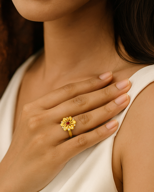 Close-up of a hand wearing a gold ring with a red gemstone, held against a neutral background.