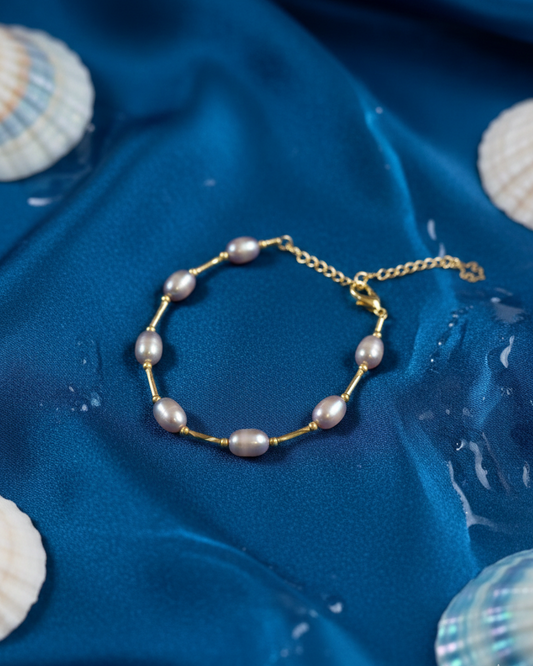 Pearl bracelet on a blue fabric background with seashells