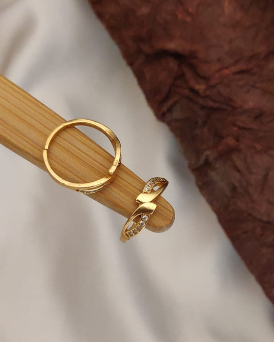 Gold ring with a bow design on a wooden stick against a neutral background