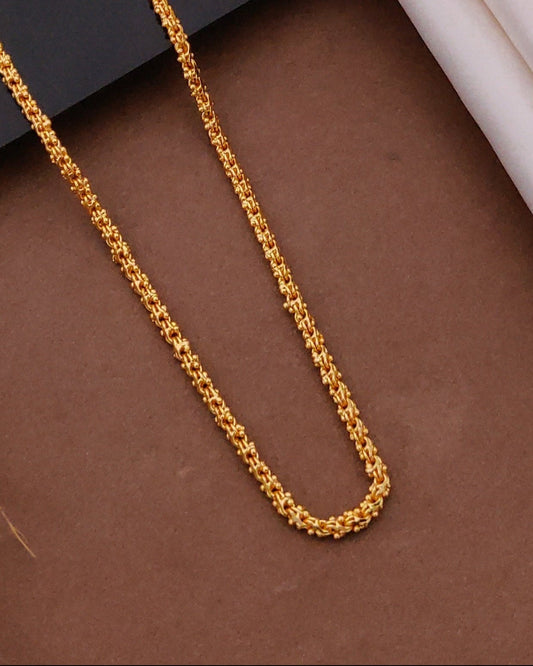 Gold chain on a dark surface with a wooden frame in the background
