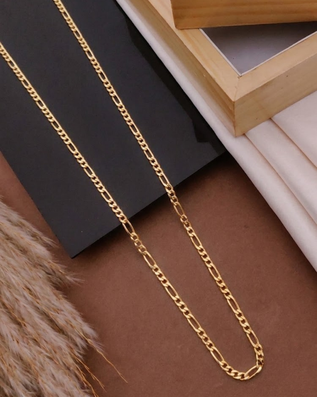Gold chain on a textured surface with a wooden frame in the background