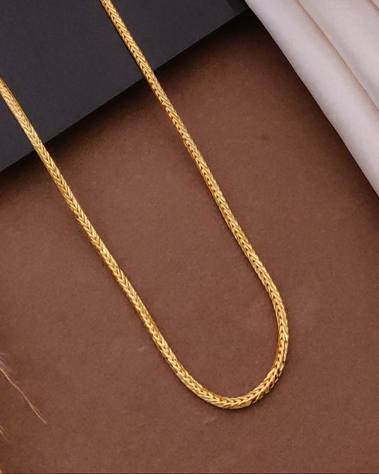 Gold chain on a textured surface with a wooden frame in the background