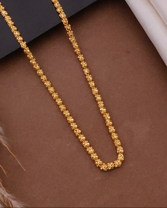 Gold chain on a textured surface with a wooden box in the background