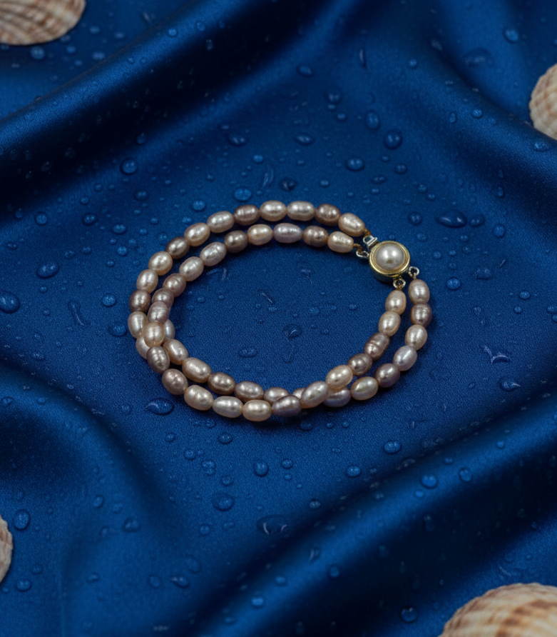 Pearl bracelet on a blue textured surface with seashells