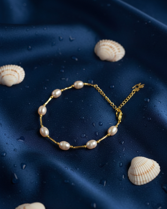Pearl bracelet on a dark blue fabric background with seashells