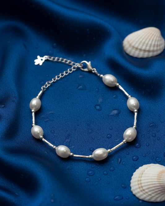 Silver bracelet with pearls on a blue fabric background with shells