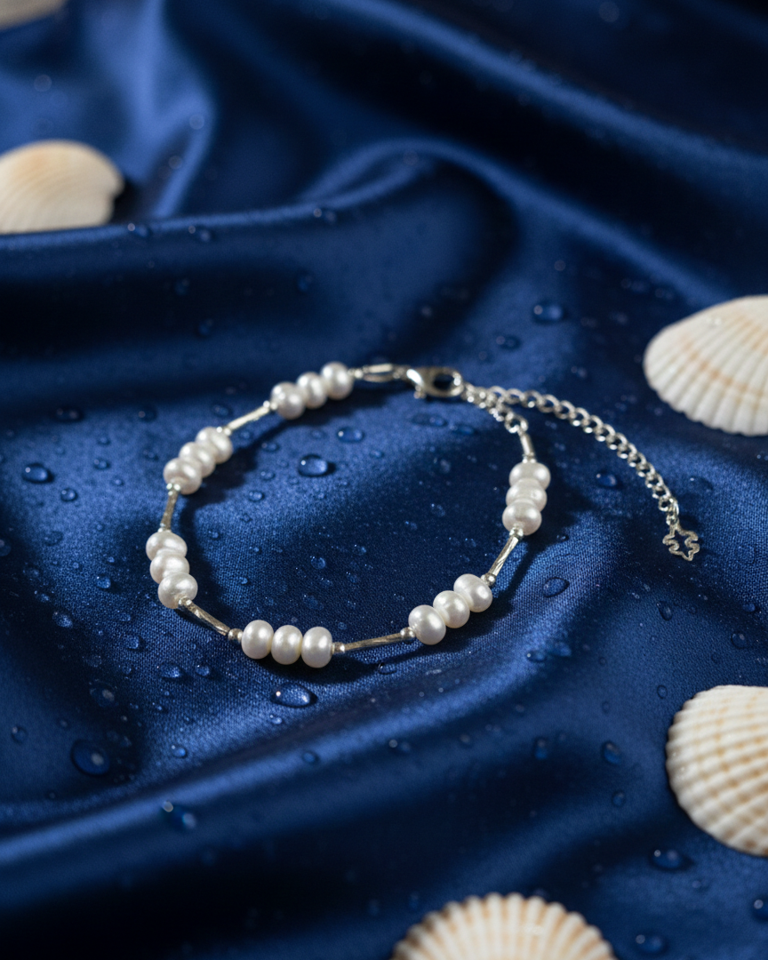 Pearl bracelet on a blue satin surface with seashells